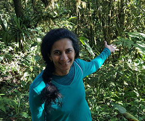 Happy Volunteer showing rainforest in the background - Rainforest Partnership