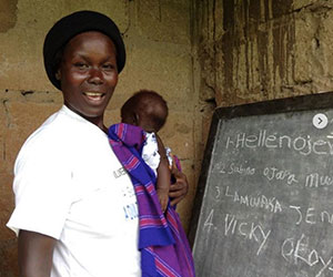 Mother holding her infant while participating in a literacy program- Womens Global Empowerment Fund