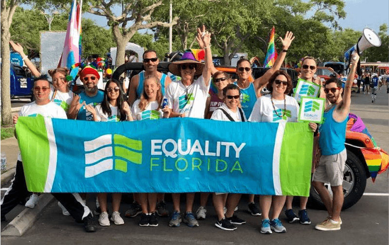 People with rainbow flags holding a sign that reads Equality Florida