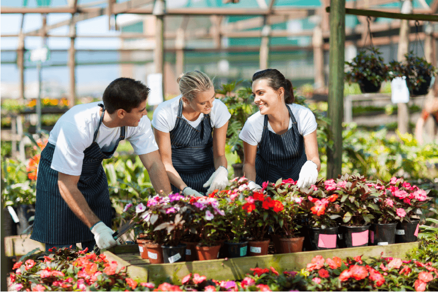 three people smiling at each other while gardening