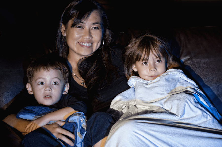 woman watching a movie with her 2 children on the couch