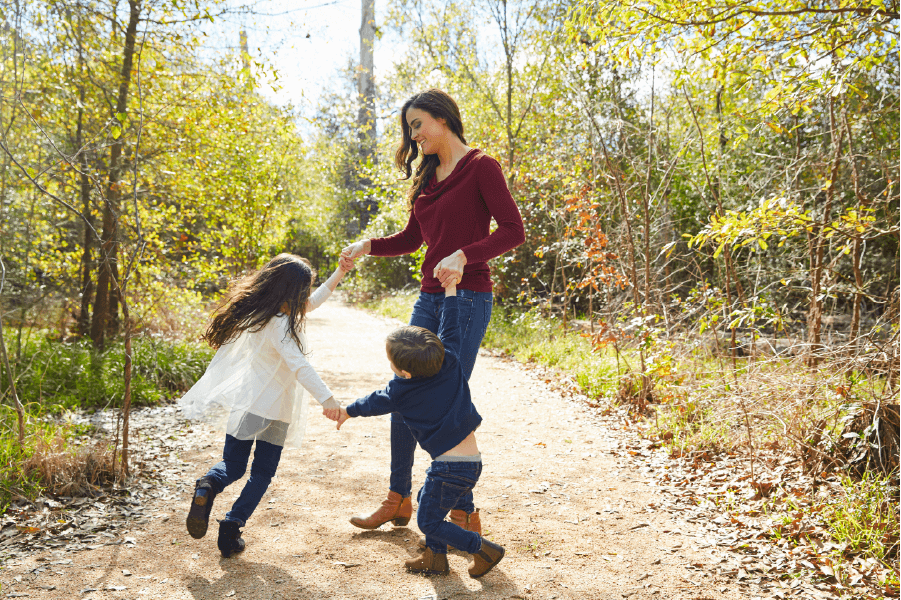 Woman holding hands with dauther and son while doing cirlcles at local trail - GreatNonprofits