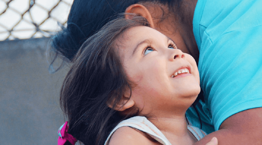 Mom reaching down to hold smiley daughter