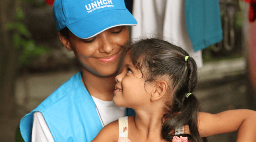 UNHCR volunteer hugging young girl