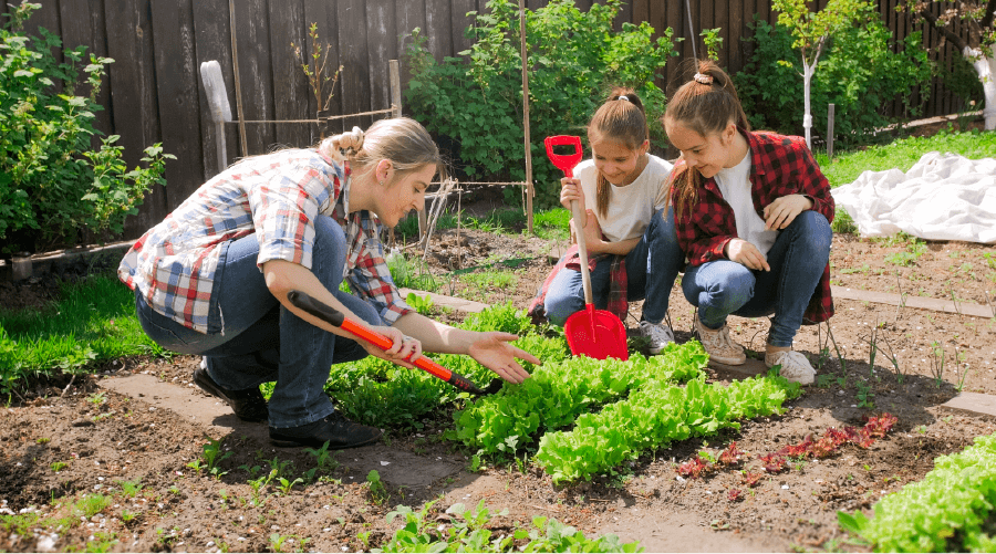 woman showing two young girls how to garden