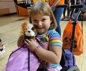 little girl in a wheelchair holding her stuffed toy Joy in the Cause