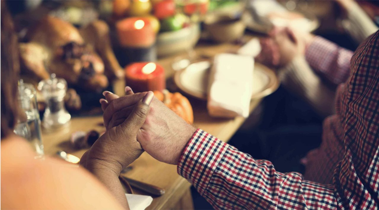 two people holding hands at Thanksgiving table