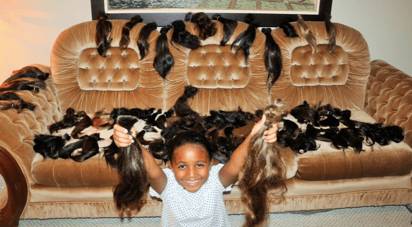 A young girl holds donated hair.