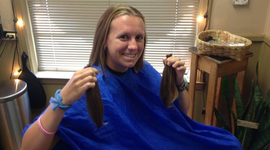 A girl sits in a hair stylist's chair after having her hair cut.