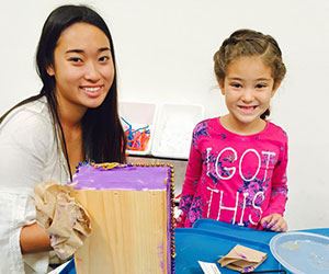 volunteer helping a little girl with her art work Child Creativity Lab