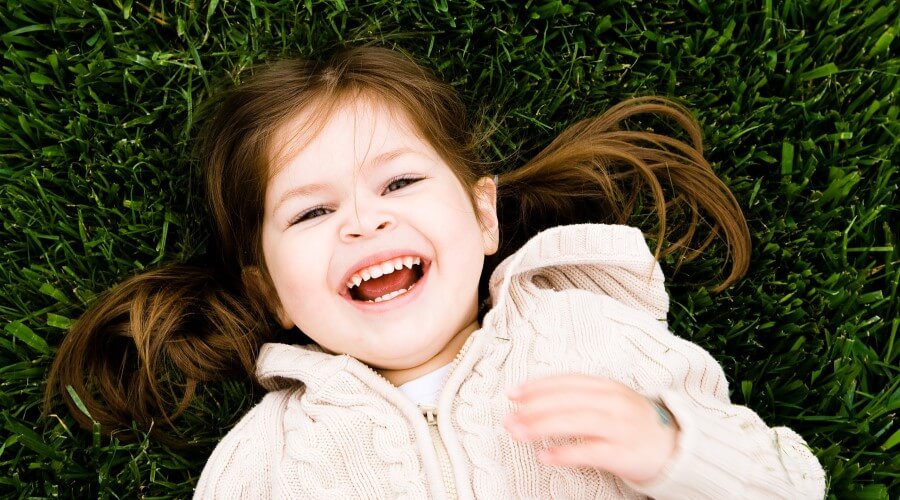 A girl smiles while lying in the grass