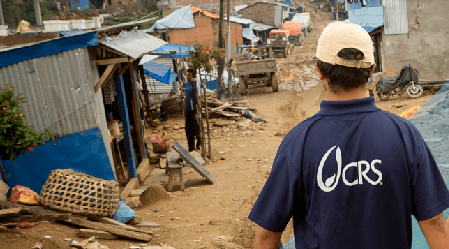 Man wearing Catholic Relief Services shirt facing disaster hit area